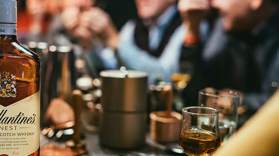 In Lokalen werden vor allem Shots oft in rauen Mengen getrunken. Im Bild zu sehen ist ein Bartresen an dem mehrere Menschen sitzen und Shots mit Alkohol konsumieren.
