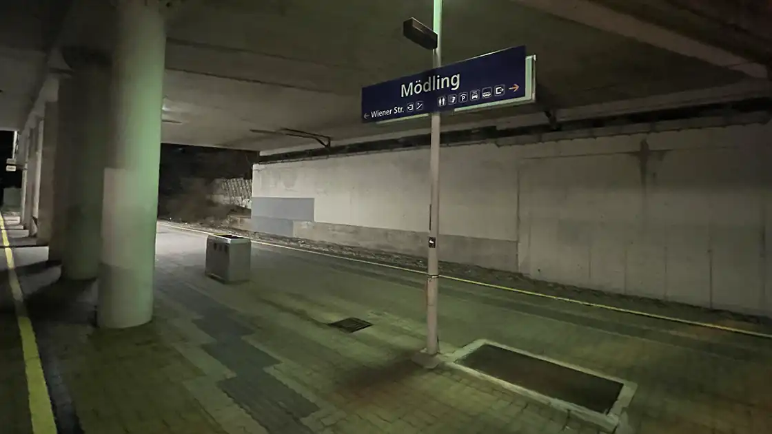 Bahnhof in Mödling am Abend mit dem Bahnhofsschild.