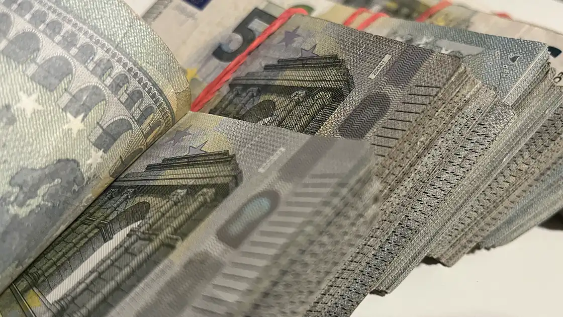 Ein vierstelliger Euro-Betrag in zusammengebundenen Bündeln von 5-Euro-Scheinen ist im Bild zu sehen. Das vorderste Bündel wird gerade durchgeblättert.