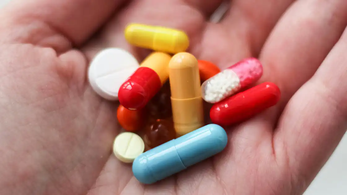 Tabletten und Medikamente in großer Menge sind Thema hier. Durch intensive Nutzung von Tabletten und Medikamenten und manchmal auch Drogen kann es zu einem Suchverhalten kommen. In einer Hand wird eine bunte Mischung aus Tabletten gehalten.