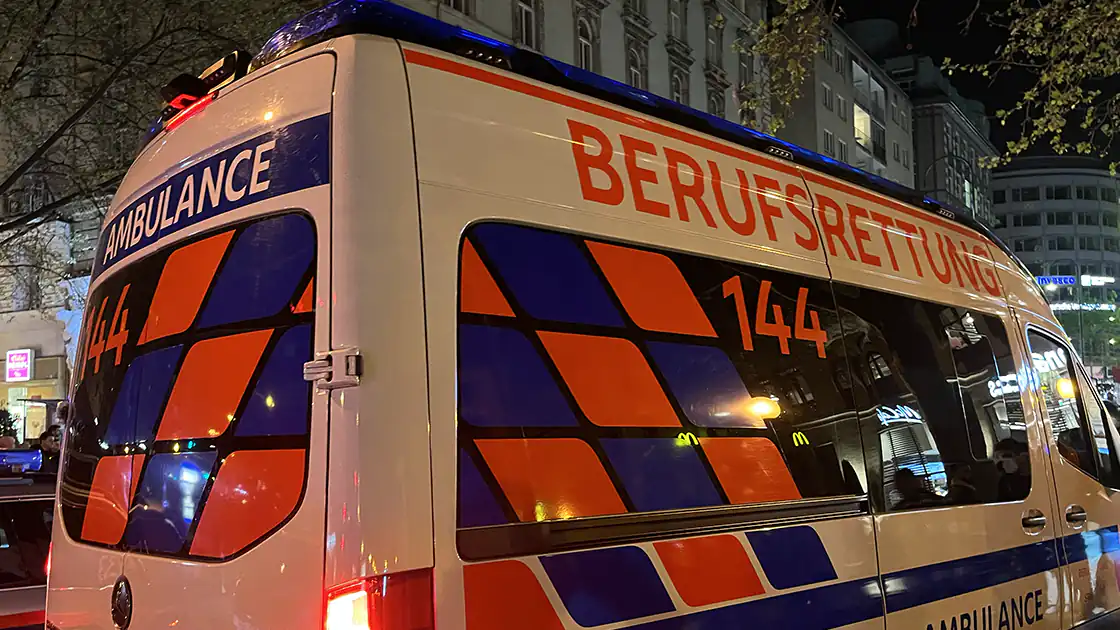 Ein Einsatz von einem Rettungsauto begleitet von Polizei in der Nacht. Die Polizei ist nur im Hintergrund des Bildes erkennbar, das Bild ist vor allem geprägt vom Rettungsauto im Vordergrund. Es trägt die Bezeichnung der Berufsrettung.