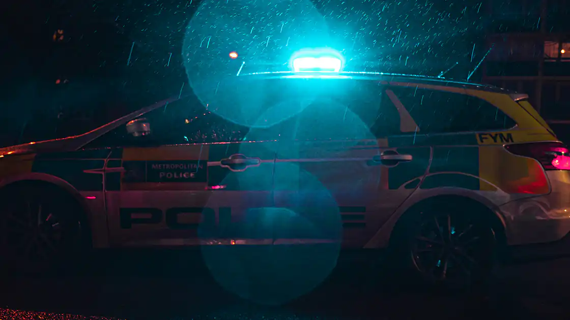 Zu sehen ist ein nächtlicher Einsatz der Polizei. Das Bild ist eine Nachtaufnahme mit einem Polizeifahrzeug, zu erkennen ist das Blaulicht am Dach des Polizeifahrzeuges.