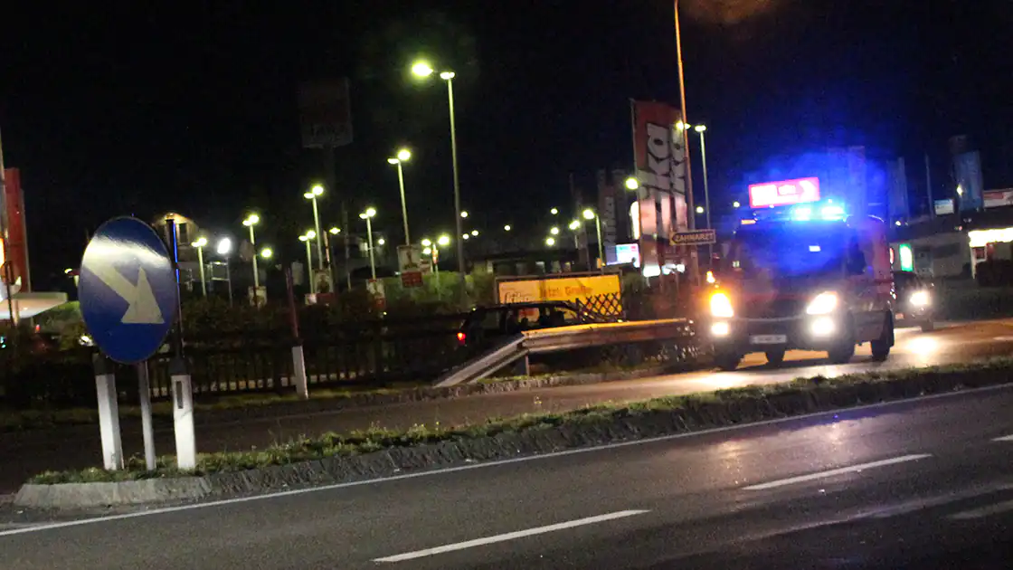 Zu sehen ist ein nächtlicher Rettungseinsatz, ein Rettungsauto auf einer Straße ist in der Nacht mit Blaulicht untewegs.