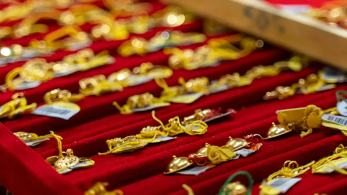 Schmuck und Juwelen sind auf diesem Bild zu sehen. Es handelt sich um ein Foto aus einem Juweliergeschäft, die Schmuckstücke aus Gold und Silber sind in einer Präsentationskiste mit rotem Satin eingelegt.