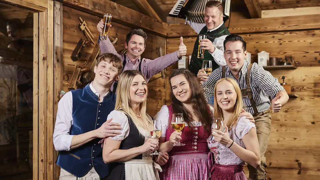 Mehrere Personen beim Feiern eines brauchtümlichen Festes, in diesem Fall die sogenannte Wiesn, bei der vor allem viel Bier getrunken wird.