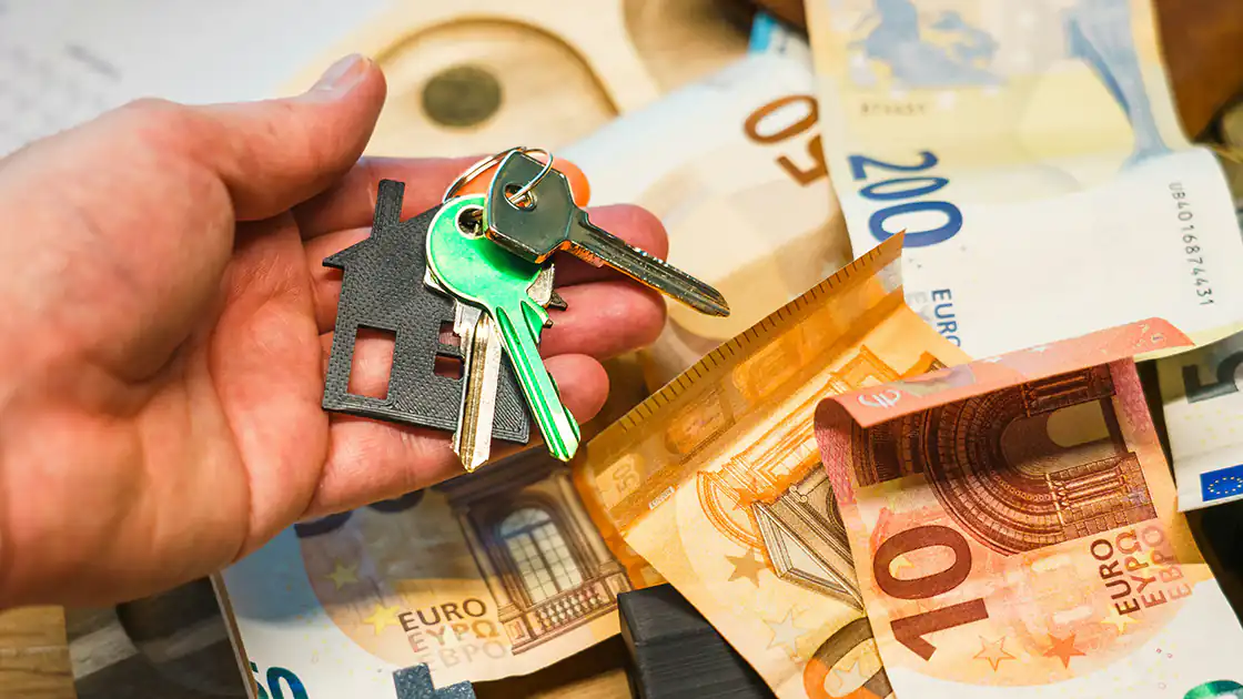 Eine Menge an Bargeld liegt herum und davor hält eine Person mit der Hand einen Schlüsselbund.