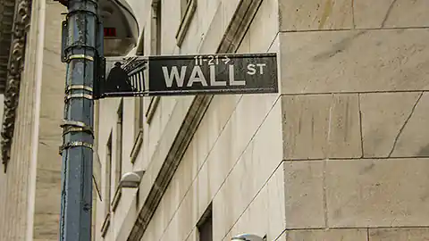 In diesem Detailbild ist an einer Hausecke das Straßenschild der Wall Street in New York City zu sehen. Das Straßenschild, das die Straße der Börse im Stadtteil Manhatten symbolisiert ist auch ein Symbol für Aktien, Börsen, Wertpapiere, Reichtum und Kriesen gleichzeitig.