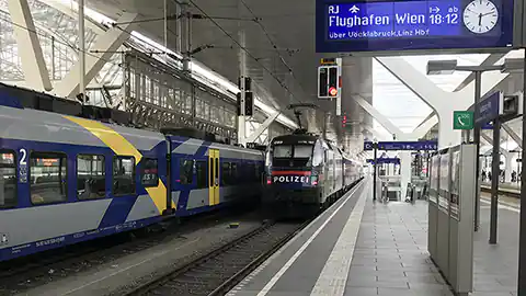 Gleise und Züge auf dem Bahnhof in Salzburg. Der Hauptbahnhof von Salzburg mit Zügen, der Zug in der Mitte ist als Polizeizug angemalt, es handelt sich dabei um Werbung für die Polizei, denn der Zug selbst ist ein ganz normaler Passagierzug.