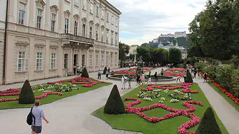 Salzburg Stadt und der berühmte Mirabellgarten sowie das - links im Bild zu sehen - Schloss Mirabell gehören zu den Wahrzeichen von Salzburg. Der Schlossgarten ist im französischen Stil gehalten, die Pflanzen sind in geometrischen Formen geschnitten.