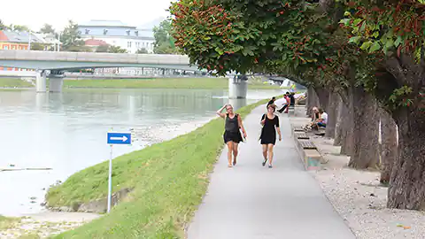 Salzburg Stadt, das Ufer der Salzach und die Brücke im Hintergrund zu sehen. Auf der rechten Seite sieht man den Fußweg, der sich am linken Altstadt-Ufer entlang der Salzach befindet.