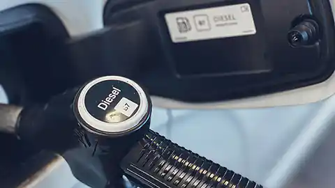 Nahaufnahme einer Tanköffnung bei einem Auto. Die Tankluke ist geöffnet und es wird Diesel an einer Tankstelle getankt.